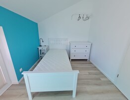 Un dormitorio con cama, mesita de noche, cómoda y lámpara de pared.