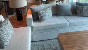 A modern living room with a sofa, a dining table, and a large window. - Vidanta AAA 5 Star Diamond Resort - 1 BR Suite  w/ Daily 2 for 1 Golf Passes (Nuevo Nayarit)