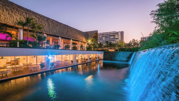 A hotel with a pool, a waterfall, and a building with a thatched roof. - Vidanta AAA 5 Star Diamond Resort - 1 BR Suite  w/ Daily 2 for 1 Golf Passes (Nuevo Nayarit)