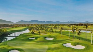 A golf course with sand bunkers, palm trees, and a water hazard. - Vidanta AAA 5 Star Diamond Resort - 1 BR Suite  w/ Daily 2 for 1 Golf Passes (Nuevo Nayarit)
