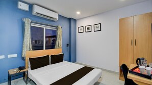 Una camera d'albergo con un letto, una scrivania con un vassoio di oggetti, un armadio e una finestra con tende.