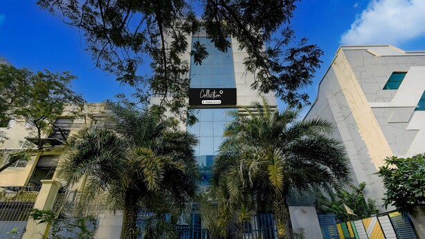 Un edificio moderno con facciata in vetro, palme e un cartello con la scritta 'Collection'.