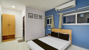 Una camera da letto con un letto, un armadio, un condizionatore d'aria e una finestra con tende.