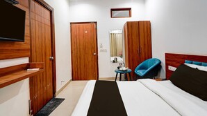 Habitació d'hotel amb un llit, una televisió penjada a la paret, un armari, un mirall i una cadira.
