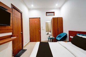 Ein Hotelzimmer mit Bett, Wandfernseher, Kleiderschrank, Spiegel und Stuhl.