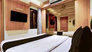 Una camera d'hotel con un letto grande, una televisione a schermo piatto fissata al muro, uno specchio e una finestra con tende.