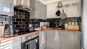 Une cuisine moderne dotée d’appareils électroménagers en acier inoxydable, d’un dosseret carrelé en noir et blanc et d’un plan de travail en bois.