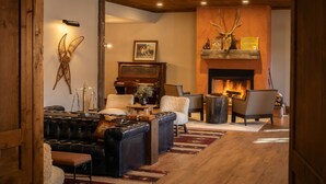 A cozy living room with a fireplace, a piano, and a leather sofa.