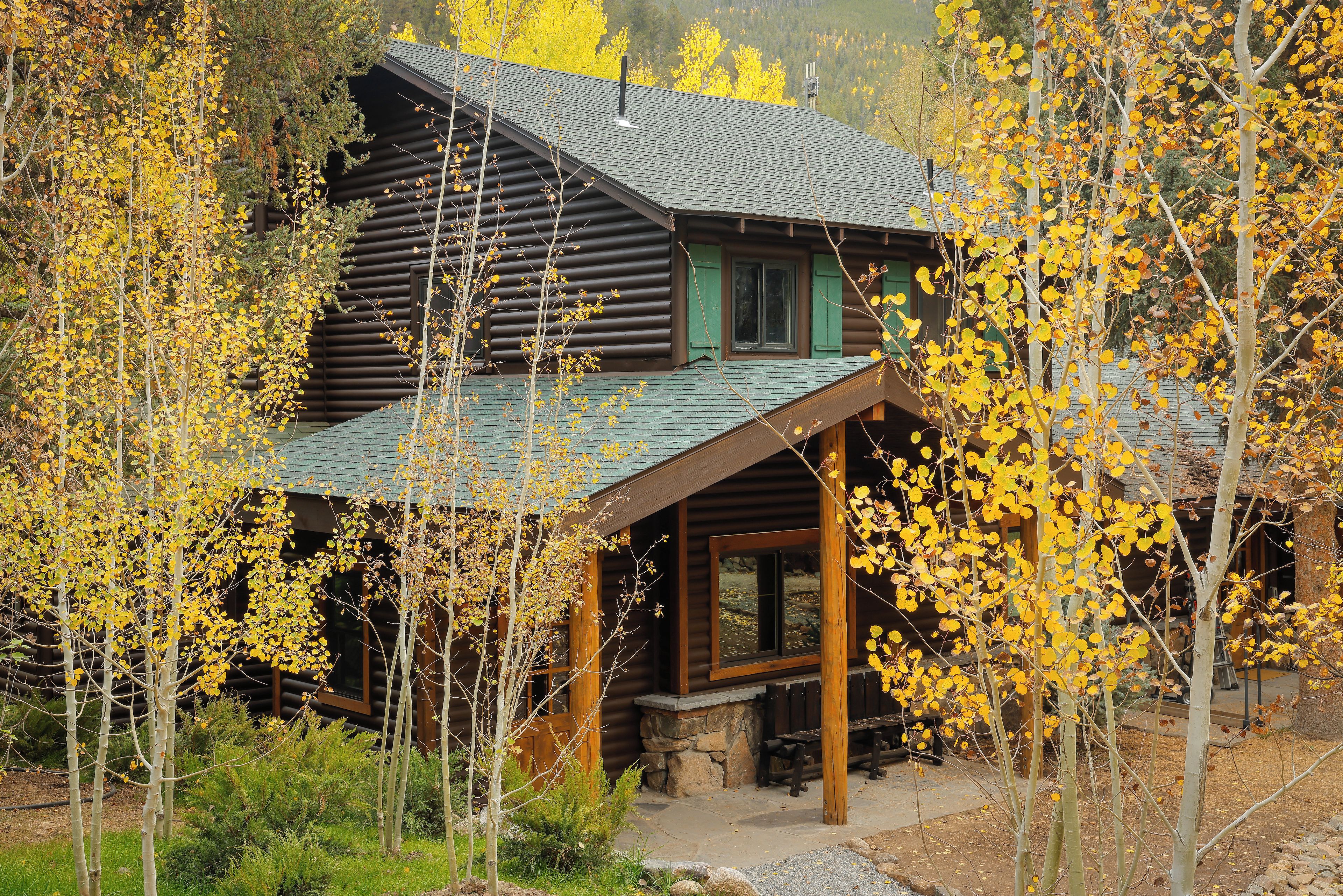 A log cabin with a porch and a stone fireplace.
