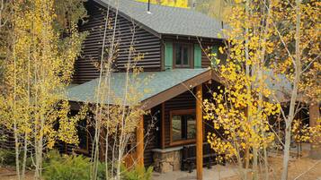 A log cabin with a porch and a stone fireplace.