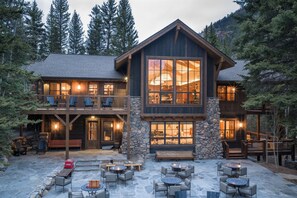 A two-story lodge with a stone facade, multiple windows, and outdoor seating areas.