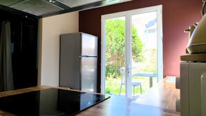 Eine Küche mit einem schwarzen Induktionskochfeld, einem Edelstahl-Kühlschrank und einer Schiebetür zu einer Terrasse.