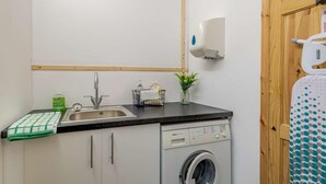 A compact kitchen with a sink, a dish soap dispenser, a small potted plant, and a washing machine. - 2 Bed in Louth (oc-86797) (Fotherby)