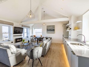 Ein geräumiger Wohnbereich mit Sofa, Sesseln, Esstisch und Fernseher.