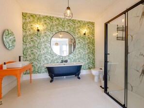 A bathroom with a freestanding bathtub, a round mirror, and a toilet. - 6 Bed in Ilfracombe (oc-86780) (Ilfracombe)
