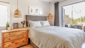 Ein Schlafzimmer mit einem Bett, einem Holzschrank, Pendelleuchten und einem Fenster mit Vorhängen.