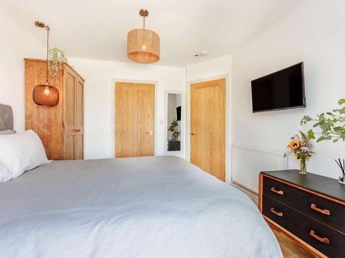 Ein Schlafzimmer mit einem großen Bett, einem Holzschrank, einem Fernseher und einer Kommode.