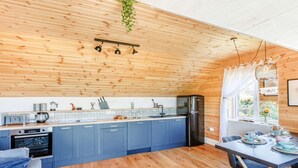 Eine moderne Küche mit Holzbalkendecke, blauen Schränken und einem Essbereich mit Tisch für zwei Personen.
