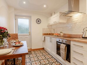 A compact kitchen with white cabinets, a tiled backsplash, a wooden countertop, and a built-in oven.
