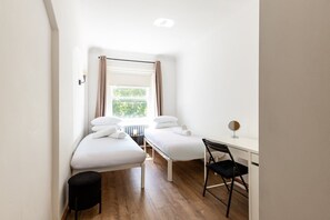 A small, clean room with two beds, a desk, and a chair. - Knightsbridge Apartment by Harrods (London)