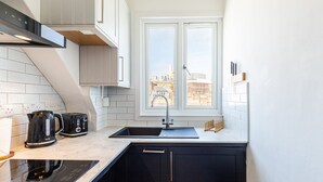 Een moderne keuken met raam, spoelbak, fornuis en waterkoker.