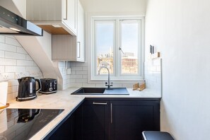 A modern kitchen with a window, a sink, a stove, and a kettle. - Knightsbridge Apartment by Harrods (London)