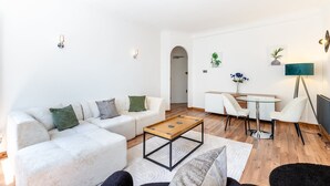 Een moderne woonkamer met een bank, salontafel en een eethoek met stoelen en een tafel.