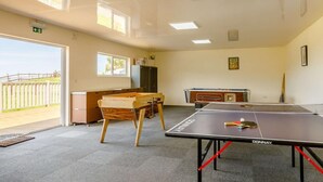 Una habitación con mesa de ping pong, mesa de madera y mesa de billar.