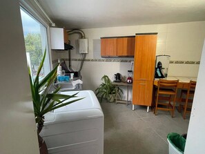 Eine kleine Küche mit Waschmaschine, Kaffeemaschine und Kühlschrank.