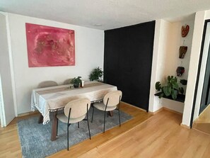 Ein Essbereich mit Tisch, Stühlen, einem Teppich und einer Wand mit einem roten, abstrakten Gemälde.