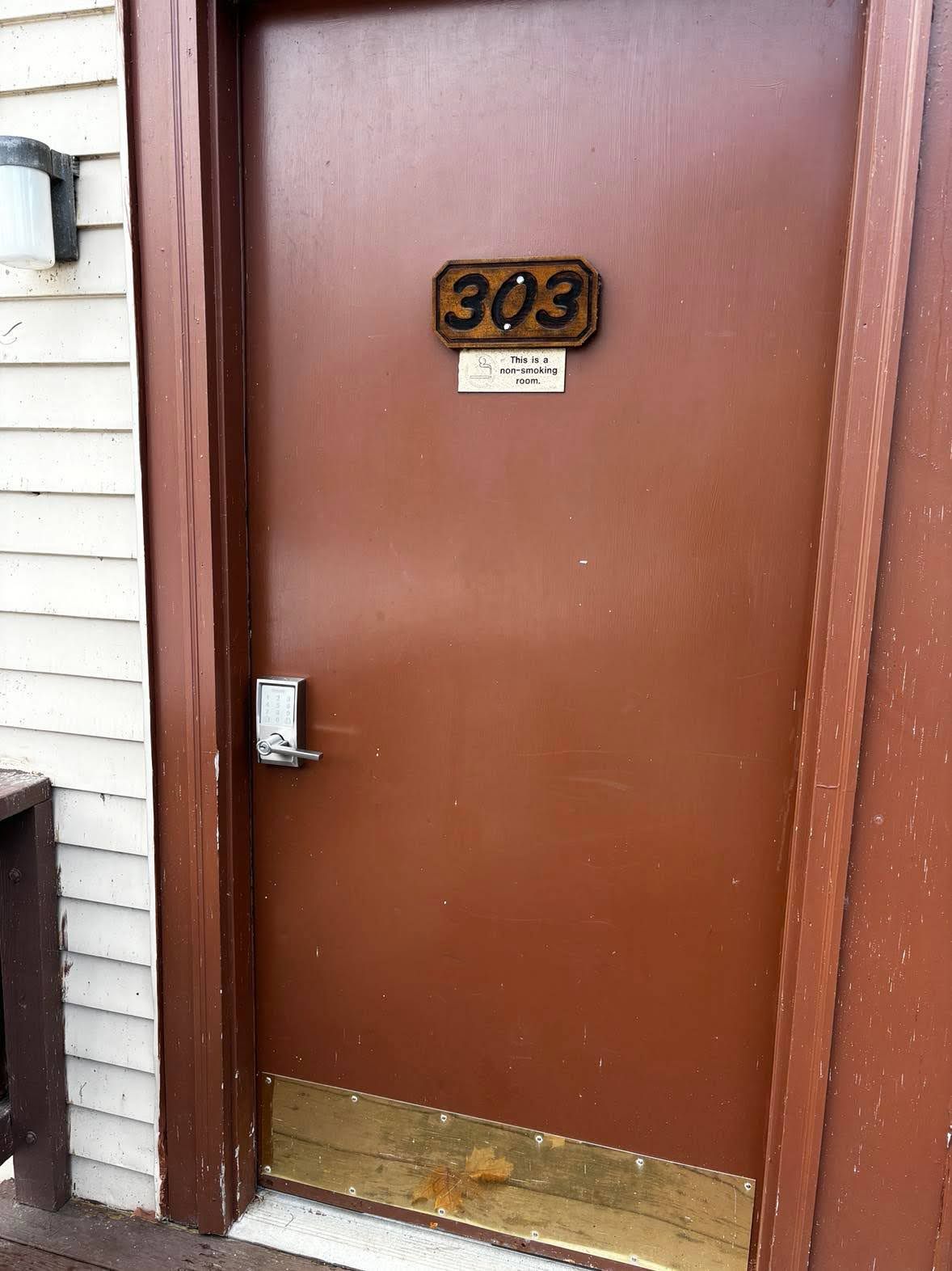 A brown door with a brass number plate reading '303' and a sign stating 'This is a non-smoking room.'