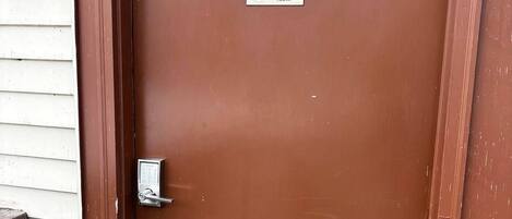 Una puerta marrón con una placa de latón con el número '303' y un cartel que indica 'Habitación para no fumadores'.