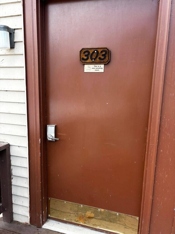 A brown door with a brass number plate reading '303' and a sign stating 'This is a non-smoking room.'