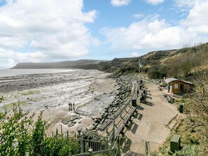 A coastal walkway with benches and a small shelter, overlooking a rocky beach and the sea. - 2 Bed in Whitby (oc-87059) (Robin Hood's Bay)