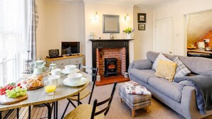 A cozy living room with a fireplace, a dining table set with breakfast, and a comfortable sofa. - 2 Bed in Whitby (oc-87059) (Robin Hood's Bay)