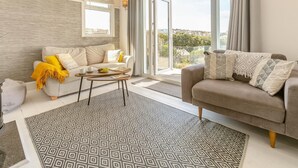 A modern living room with a sofa, coffee table, and patterned rug. - 3 Bed in Perranporth (oc-87126) (Perranporth)