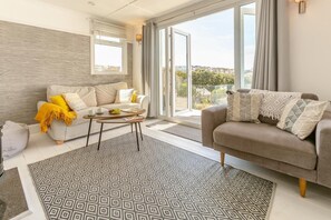 Ein modernes Wohnzimmer mit Sofa, Couchtisch und gemustertem Teppich.