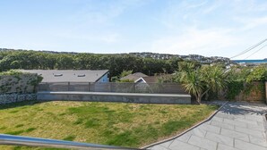 A residential backyard with a paved patio, a stone wall, and a grassy lawn. - 3 Bed in Perranporth (oc-87126) (Perranporth)