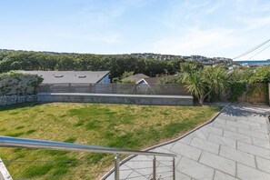 Ein Wohngarten mit gepflasterter Terrasse, einer Steinmauer und einem Rasen.
