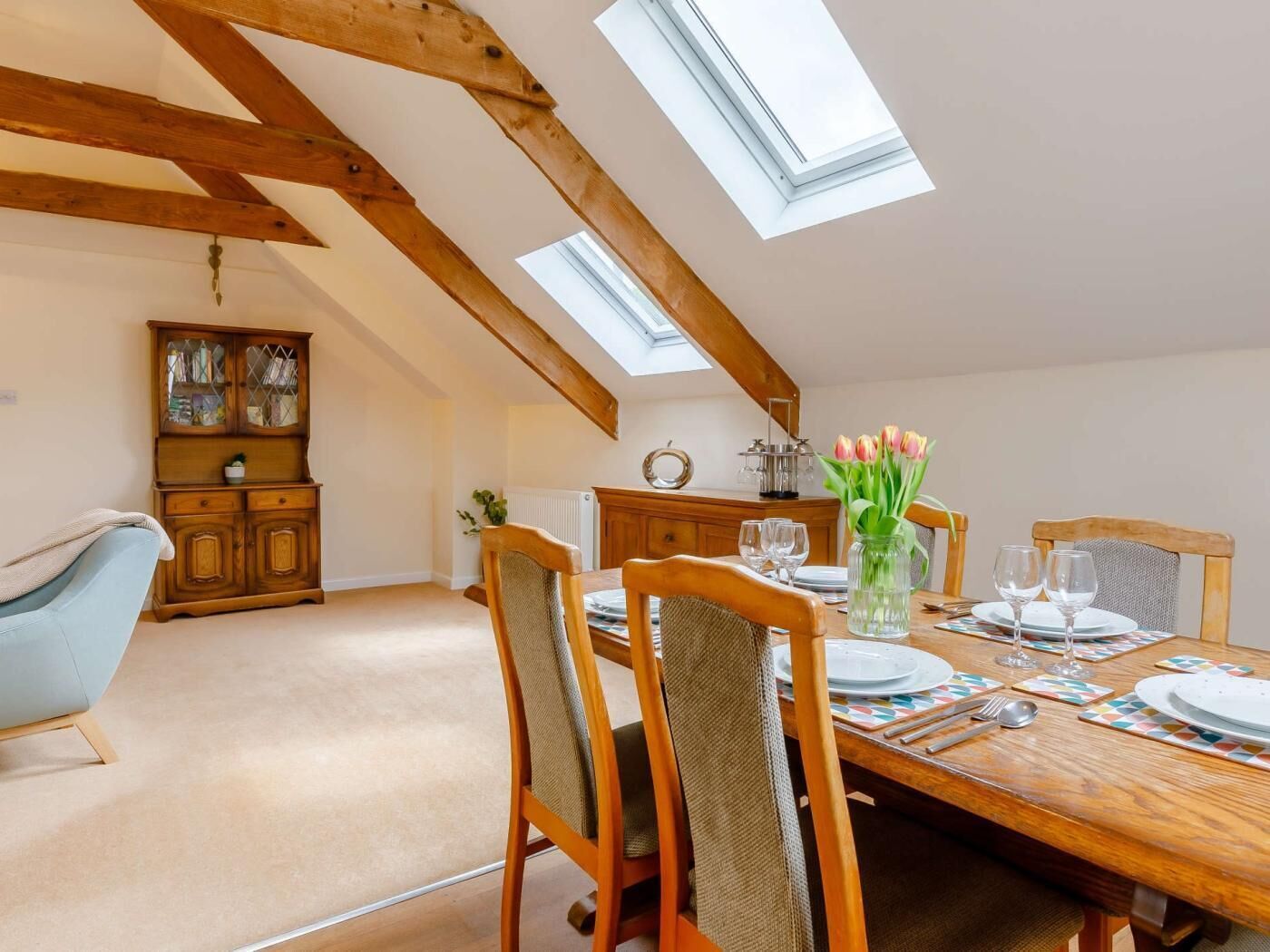 Un espace repas doté d’un plafond haut, de lucarnes, de meubles en bois et offrant une vue sur le ciel.