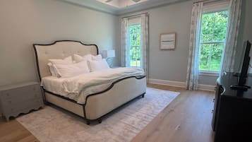 Une chambre à coucher avec un lit, un ventilateur de plafond, une commode et une fenêtre avec des rideaux.