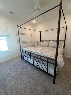 A four-poster bed with a canopy, a ceiling fan, and a window with a view.