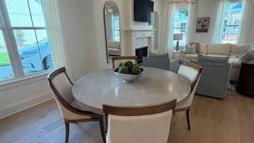 Un coin repas avec une table ronde et des chaises, une cheminée et un téléviseur fixé au-dessus.
