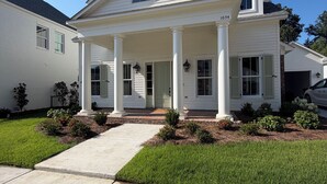 A two-story house with a front porch, columns, and a small attached garage.