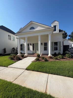 A two-story house with a front porch, columns, and a small attached garage.