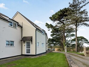 A two-story building with a flat roof, a small attached garage, and a well-maintained lawn. - 2 Bed in Bude (oc-86920) (Kilkhampton)