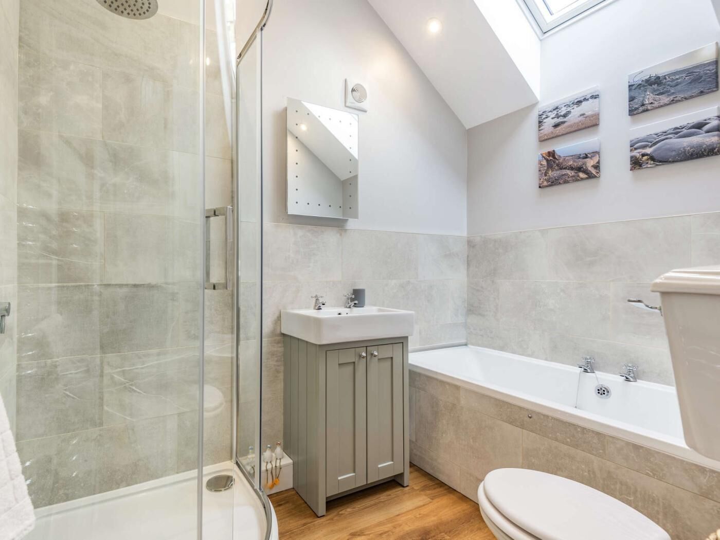 A modern bathroom with a glass shower enclosure, a freestanding bathtub, and a vanity with a mirror.