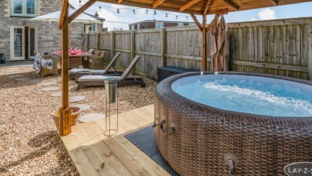 En trädgård med en bubbelpool, ett trädäck och en möblerad uteplats under tak.