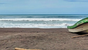 Une plage avec un bateau vert sur le sable.
