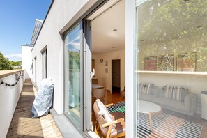 A modern apartment with a balcony, a sliding glass door leading to a living area, and a view of the city. - Bright Lambeth Apartment by Waterloo (London)